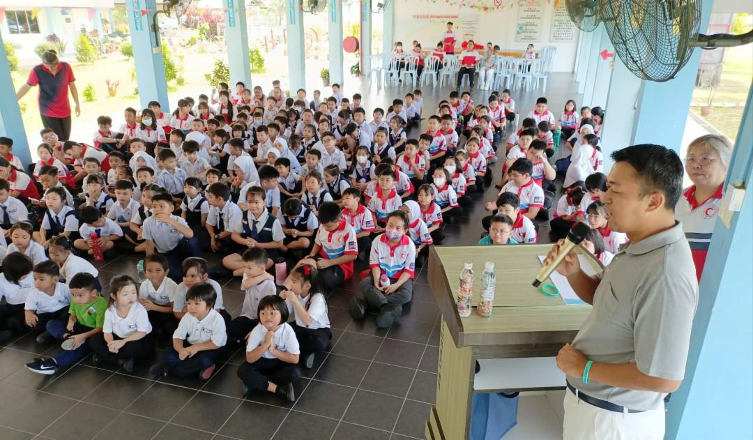 谢硕虔（前右）在向小学生讲解环保知识，并指导他们如何制作合格的环保砖。 【摄影：方文光】
