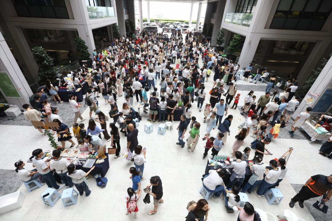 义卖会现场，人头涌动，许多小学部家长带着孩子来参与，气氛热闹。【摄影：庄贵贺】