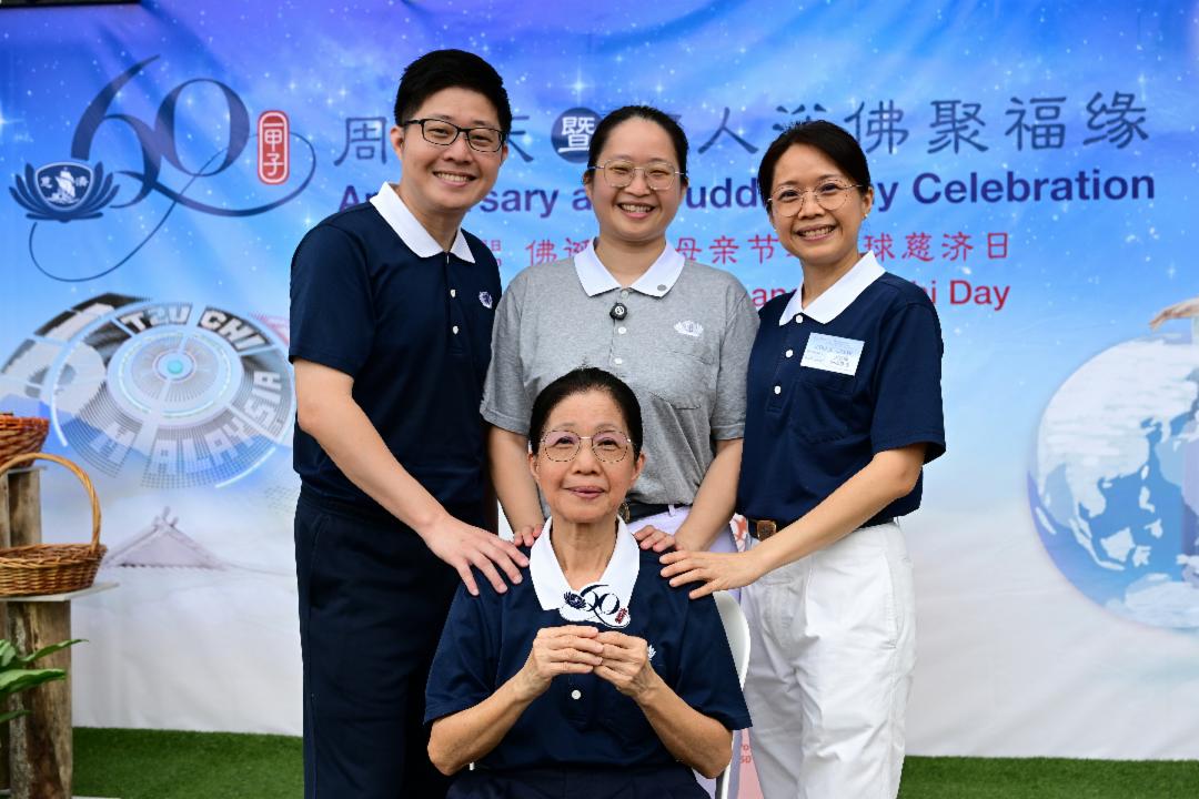 七十三岁的廖逸兰（前坐者）与儿女在慈济六十周年海报前合影，把最灿烂的笑容，定格成最珍贵、美好的回忆。 【摄影：李国强】